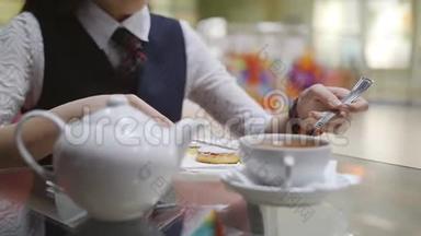 穿着校服的少女坐在<strong>学校食堂</strong>的一张桌子旁吃蛋糕，喝茶，特写。